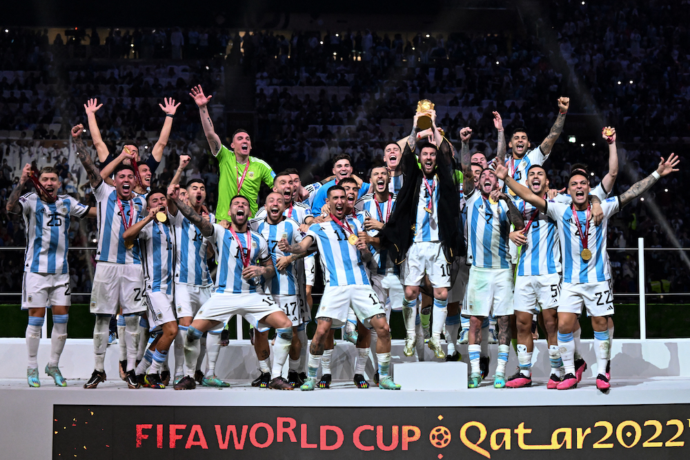 Lionel Messi ergue o troféu da Copa do Mundo da FIFA ao comemorar com seus companheiros a conquista da Copa do Mundo de 2022 no Catar